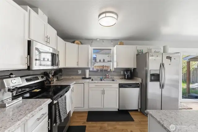 Bright kitchen with white cabinets and stainless appliances.
