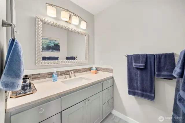 En-suite bathroom with quartz countertops and tile flooring.