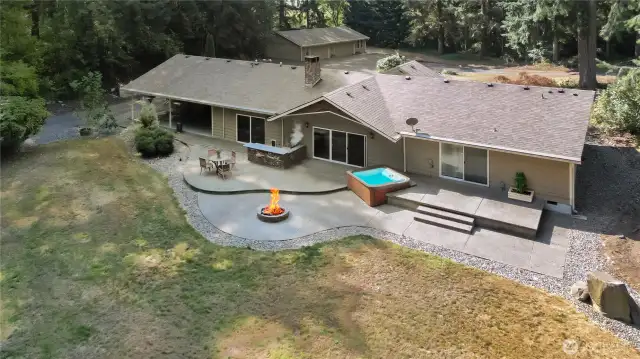 Aerial shows outdoor kitchen, large patio, deck, and fire pit.