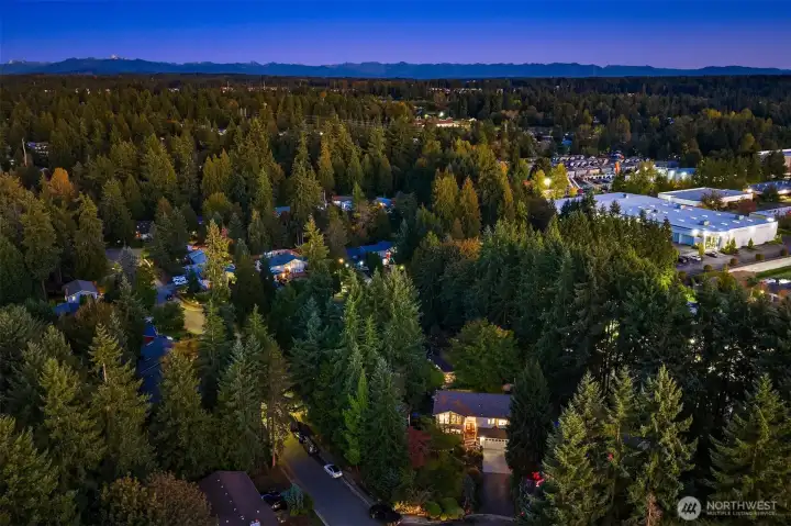 A breathtaking twilight aerial captures the perfect blend of privacy and community—nestled among evergreens with the Cascade Mountains in the distance. This serene neighborhood setting showcases the home’s prime location and beautifully illuminated presence surrounded by lush PNW forest. A rare combination of natural tranquility and convenience, just moments from local amenities and commuter routes. ??????