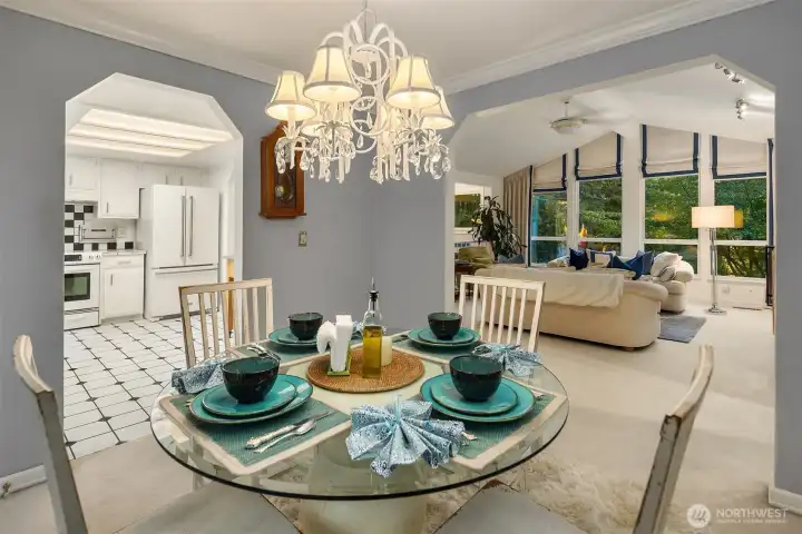 The open flow between dining, living, and kitchen spaces makes entertaining effortless. Crisp white trim, crown molding, and a statement chandelier add timeless charm, while the layout keeps every conversation connected from the table to the firelit living room.