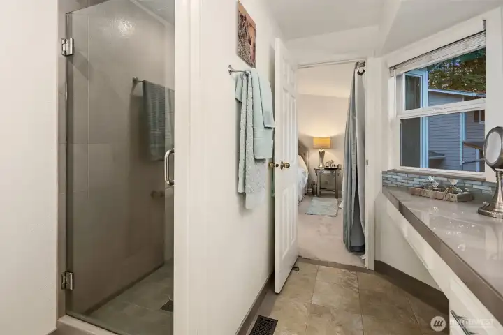 The ensuite bath showcases a sleek walk-in shower with glass enclosure and contemporary tile surround, offering both style and function. Heated tile floors add year-round comfort, while the large vanity and window bring in soft natural light for a spa-like atmosphere. A serene and beautifully finished space that perfectly complements the private primary suite. ????