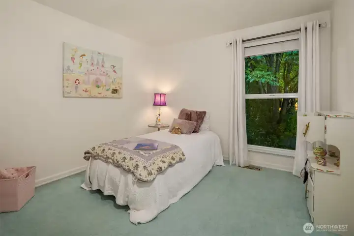 Bright and peaceful, this bedroom overlooks lush greenery through a large picture window, creating a serene backdrop for rest or play. Soft colors and natural light make the space feel open and inviting. Thoughtfully designed for comfort and flexibility. ????