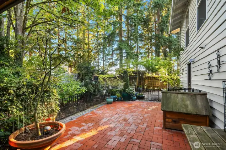 Stylish brick patio looks out onto the lush greenery.