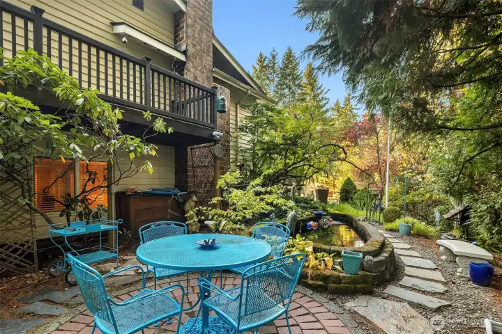 Charming brick patio tucked beside the pond—an inviting spot to dine al fresco or enjoy the sights and sounds of the garden and the trees on your property.