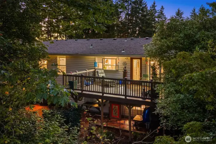 Twilight captures the warm glow of the home and its spacious upper deck surrounded by evergreens—perfect for entertaining or relaxing in your own woodland retreat. ???