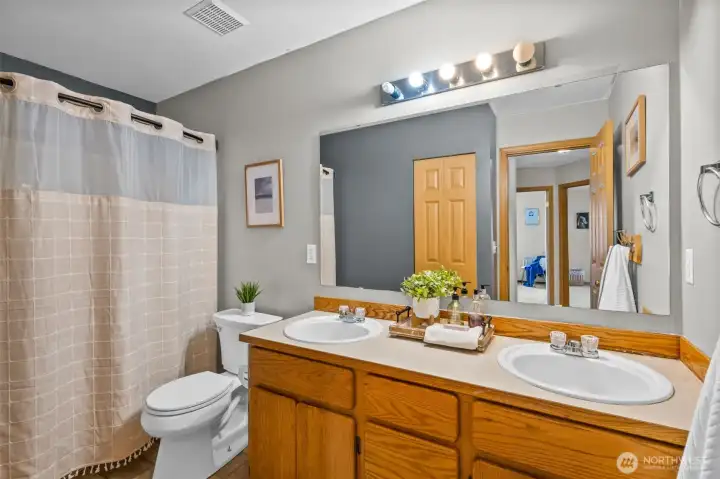 Upper full sized hall bathroom with dual sinks & storage.
