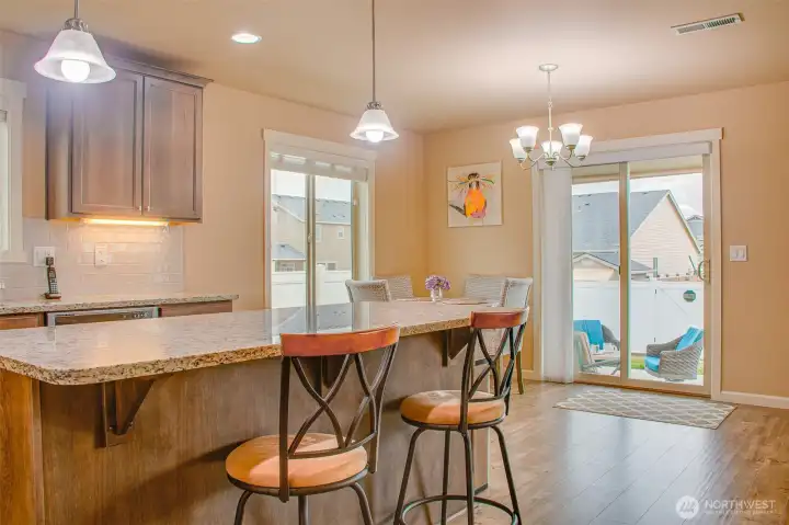 KITCHEN BAR: Bar Seating, Dining Area Beyond, and Backyard Sliding Glass Door with Vertical Blinds.