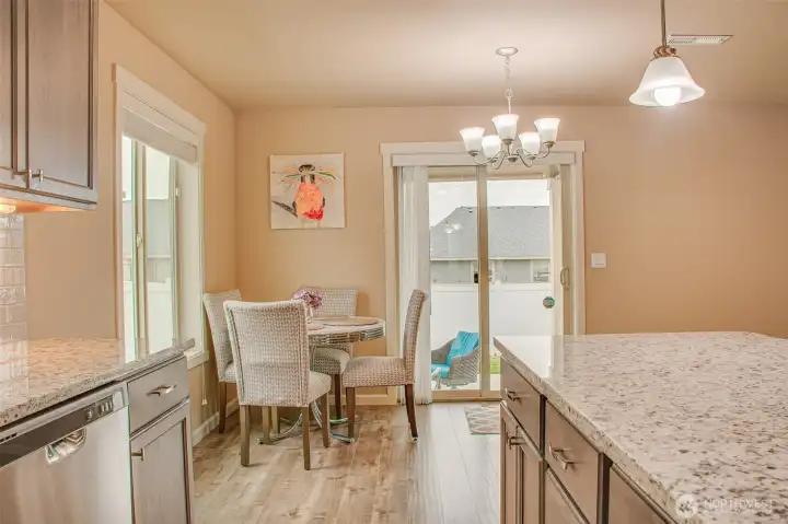 DINING SPACE FROM KITCHEN (by Range/Oven): LVP Flooring, East-Facing Window with 2" Horizontal Vinyl Blinds, South-Facing Sliding Glass Door with Vertical Blinds