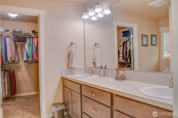 PRIMARY BATHROOM (from primary bedroom): Showing Walk-In Closet, Double Sinks, and Large Wall Mirror.  Carpet flooring in closet, Vinyl flooring in bathroom.