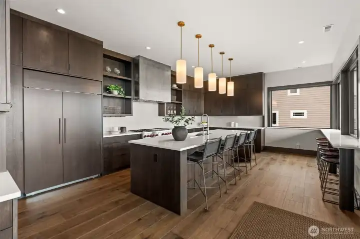 Well-appointed kitchen with large island, seating, custom cabinetry, and pendant lighting.