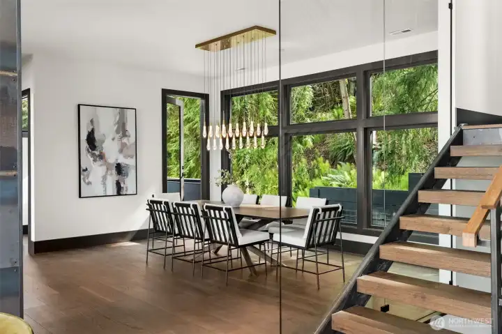 Dining area with large windows, natural light, and peaceful outlook to surrounding greenery, creating a comfortable space for gatherings.