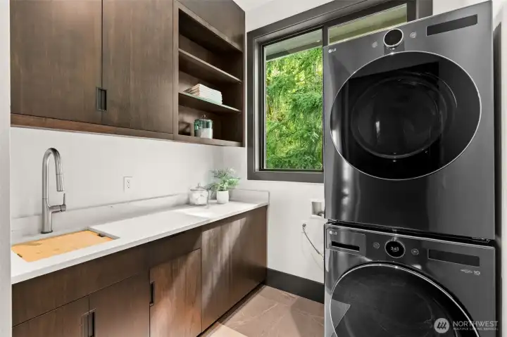 Additional laundry area with stacked washer and dryer, utility sink, and built-in cabinetry for added convenience.