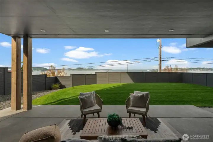 Covered patio opens to a fenced, level lawn, offering a comfortable outdoor space for relaxing or gathering.