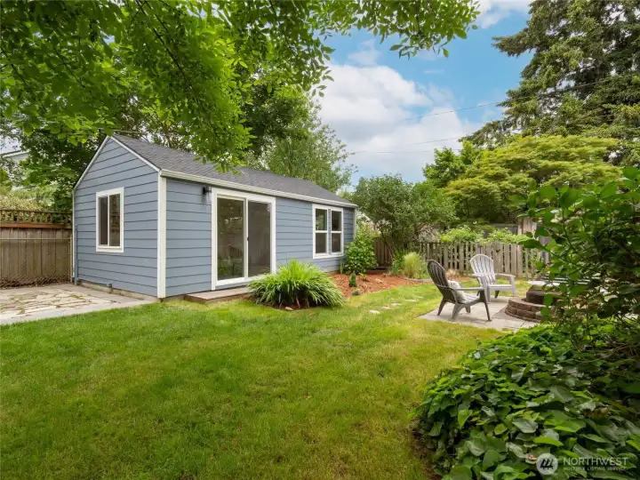 A flagstone patio, a fire pit area, and the detached studio are all laid out nicely in the backyard, surrounded by gorgeous mature plantings.