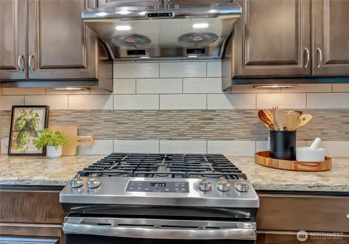 Heavy duty exhaust fan, nice stove, and cabinet-height backsplash with "just right" accent tile is a great combination as you whip up recipe ingredients to cook up a lively lasagna or delicious dish.