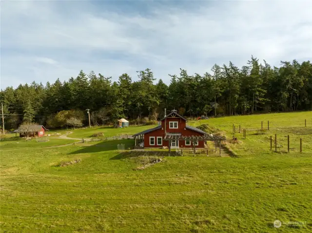 Farmhouse west exterior, farmstand to left, yurt in middle background