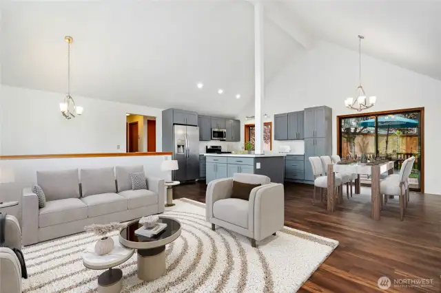Living room with vaulted ceilings, abundance of natural light with wall of windows & wood burning fireplace. (Virtually staged)