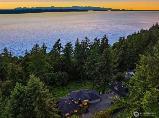 This Three Tree Point estate is cuddled by mature trees just steps from the water.