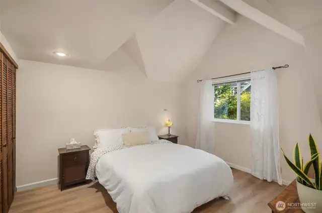 Light and airy bedroom has vaulted ceilings and window overlooking the picturesque grounds.