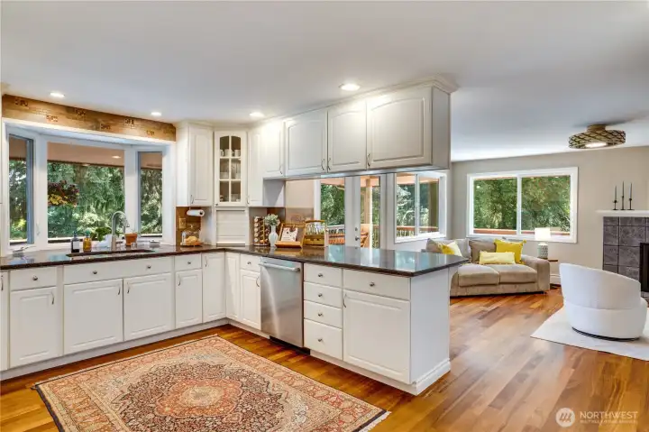 Quartz counters, a bay window, gas range, and a generous arrangement of cabinets are just a few features of this open kitchen.