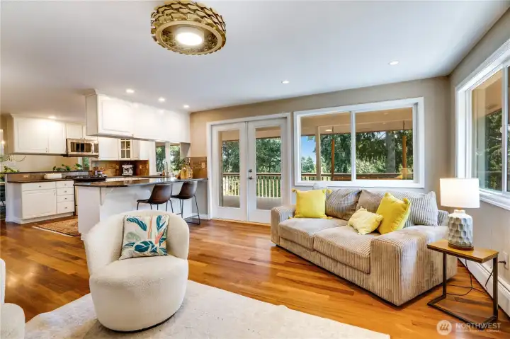 This family room beside the kitchen is illuminated by recessed lighting, an overhead fixture, and by the big windows and French doors wrapping around the room. And don't forget the warmth of the firelight too.