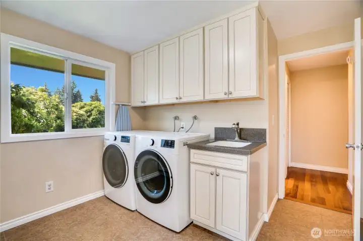 This laundry room with its new washer and dryer finishes the main floor of the home. A back door opens to the wraparound deck with a few steps down to the lawn in the fenced yard.