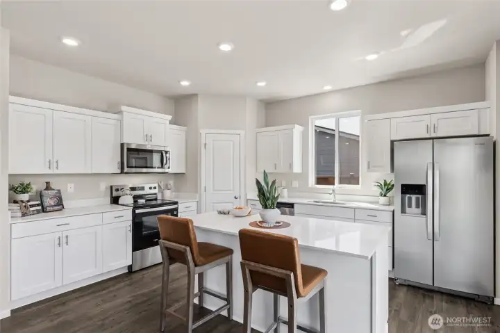 Beautifully open kitchen with stainless steel appliances and large island with breakfast bar. Actual home is under construction and finishes may vary. See site agent for details.