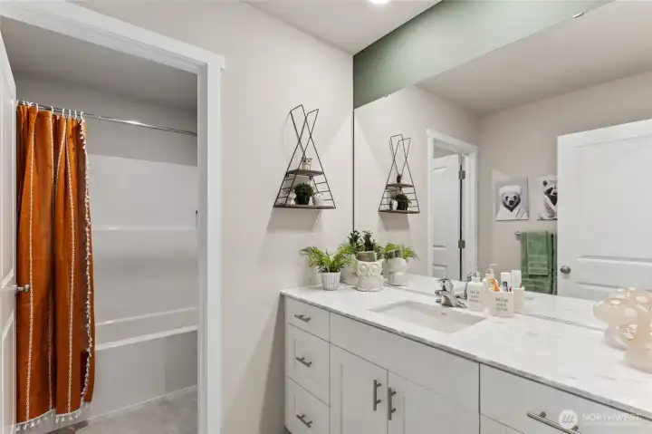 Hall bathroom with quartz top vanity and separate door to toilet and shower for convenience. Actual home is under construction and finishes, colors, and materials may vary. See site agent for details.