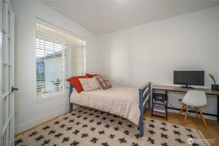This fourth bedroom, located just off the living room, is currently used as a bedroom but would also make a perfect den or office with its elegant French doors.