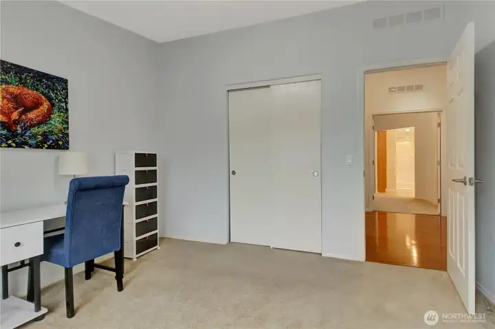 second bedroom with closet and hallway view. across the hall is the primary bedroom.