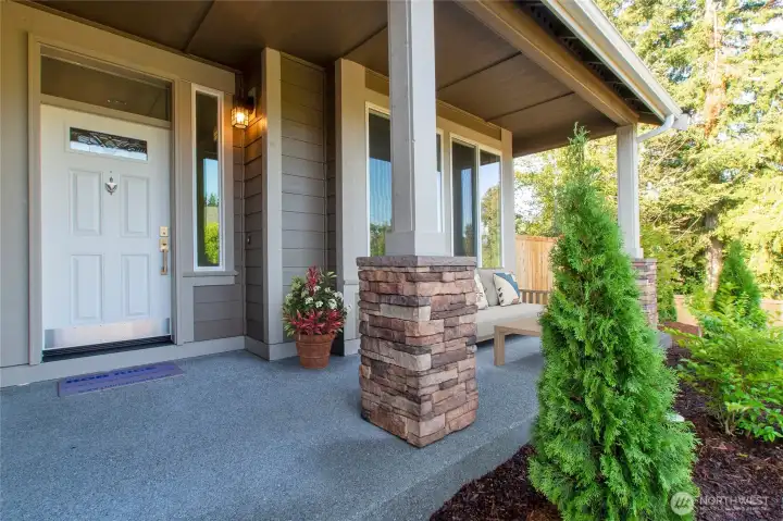Covered front porch, accented by columns with stone bases, adds architectural charm and a cozy entryway.