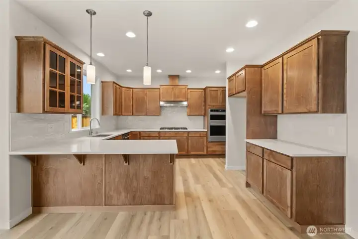 Sleek and modern kitchen with Quartz counters and full tile backsplash. Pendant lights hang above eating bar are perfect for casual meals or entertaining.