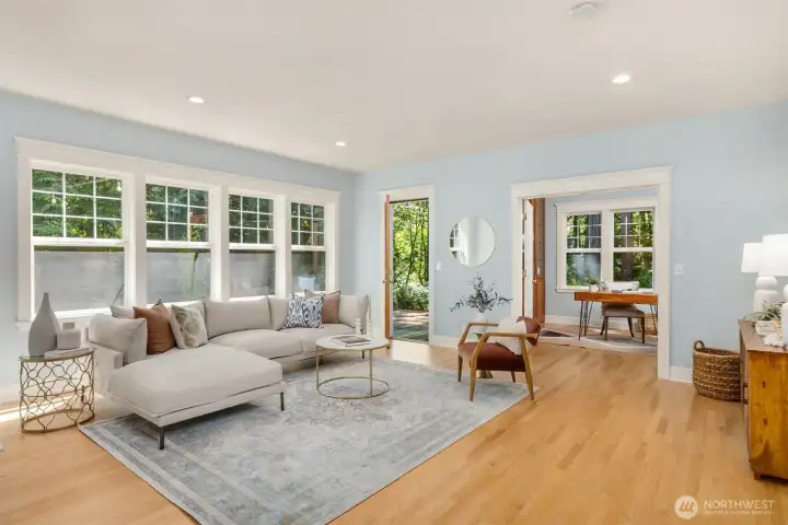 The open-concept family room has a wall of windows, multiple doors outside to the back deck, and is directly connected to the modern kitchen.