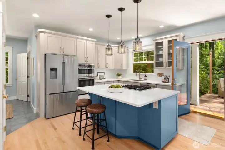 The kitchen with ample cabinetry storage, quartz counters, a subway tiled backsplash, updated appliances, a pantry and freshly painted cabinetry.