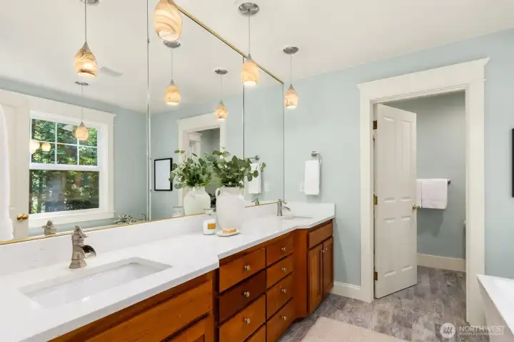The primary bathroom has been updated with quartz counters, dual sinks, tiled flooring, a soaking tub and oversized shower.