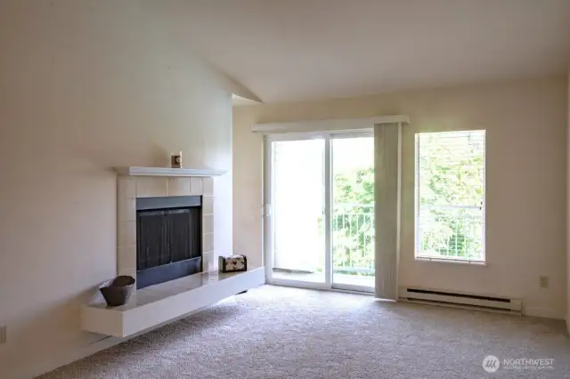 Living room with vaulted ceiling and cozy wood burning fireplace.  Slider to deck with storage.