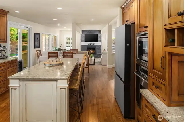 A stunning, remodeled Gourmet Kitchen with a large granite island/eating bar & stunning custom cabinets, stainless steel Dacor & Meile appliances including a 5-burner gas cooktop with a pot filler, under-cabinet lighting, planning desk space, dove-tailed wood, quiet-close drawers, subway tile backsplash, and a garden window overlooking the back yard.