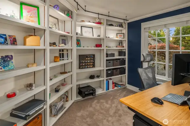The main floor office/den off of the entry features a wall of built-in, solid shelving and upgraded lighting.