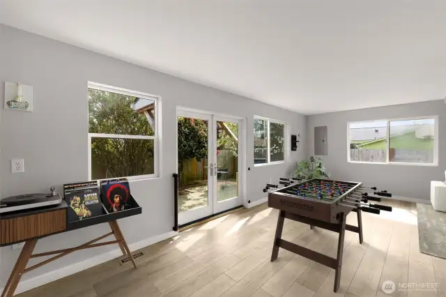 Updated sunroom with stylish flooring and backyard access. This image is virtually staged.