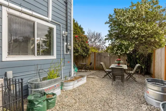 Fully fenced backyard with garden beds and mature trees. This image is virtually staged.