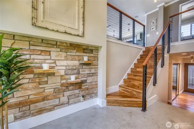 The entry way has a modern flare with concrete floors and a unique stone wall.