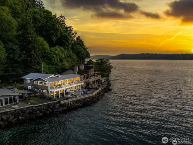Your home glows warmly in the soft light of dusk, the amber sky casting a golden veil over the water.