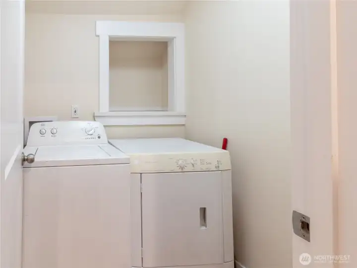 Laundry room just off from the kitchen, offers a cubby for laundry soaps, and space for cleaning supplies.