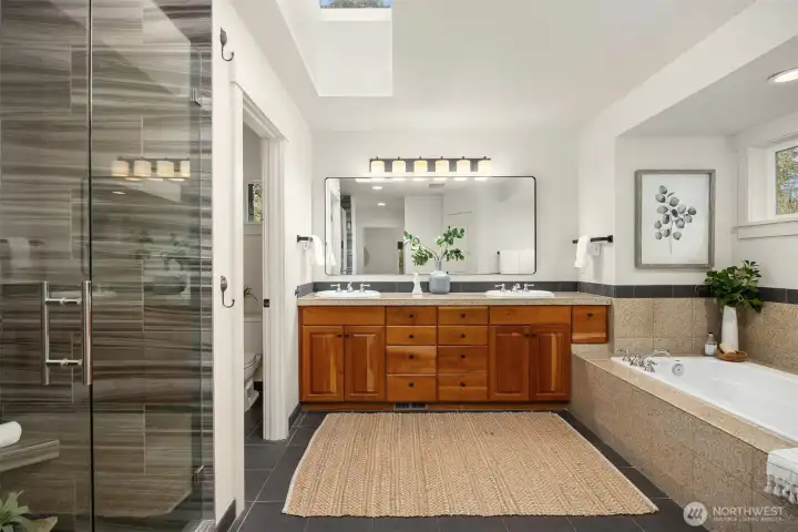 Well-appointed primary bath with dual vanity, tiled shower, and relaxing soaking tub.