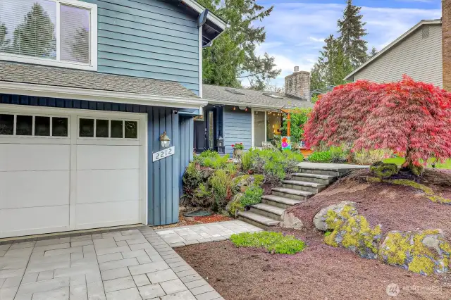 Garage doors topper with classic windows. Pavers from driveway continue the path and steps to front door.