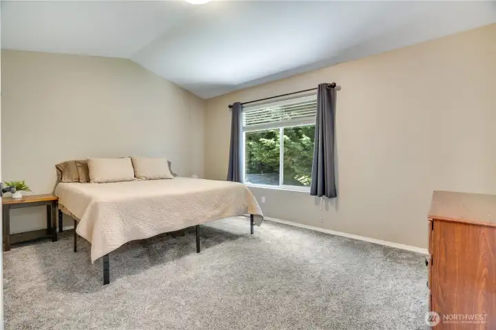 The primary suite features vaulted ceilings, a full ensuite bathroom and walk-in closet, and newer carpet!