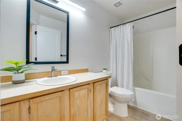 The guest full bath has an oversized vanity and stylish mirror and light fixture to coordinate with the rest of the home.