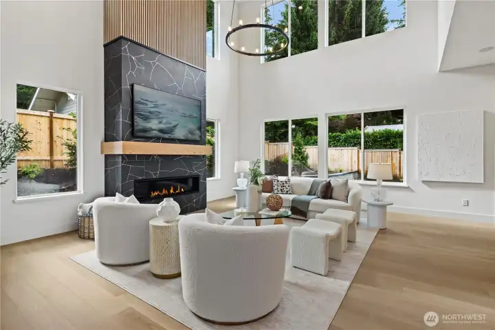 Dramatic two-story fireplace with large-format porcelain tiles, gold veining, slat panel accents, chunky wood mantle, and a newly installed razor-thin 77" Samsung TV. Designed as a statement focal wall.