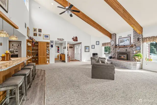 Step into a spacious great room with soaring vaulted ceilings, accented by rich wood beams, and abundant natural light, the Clerestory windows bathe the room in sunlight. At the heart of the room, a classic floor-to-ceiling brick fireplace adds warmth and timeless charm.